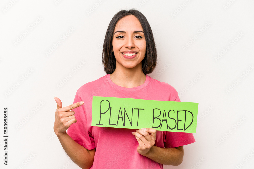 Young caucasian woman holding plant based placard isolated on white background smiling and pointing aside, showing something at blank space. Young caucasian woman holding plant based placard isolated on white background smiling and pointing aside, showing something at blank space.