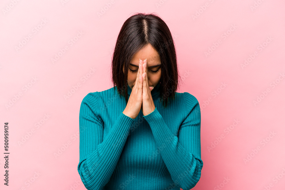 Young hispanic woman isolated on pink background praying, showing devotion, religious person looking for divine inspiration. Young hispanic woman isolated on pink background praying, showing devotion, religious person looking for divine inspiration.