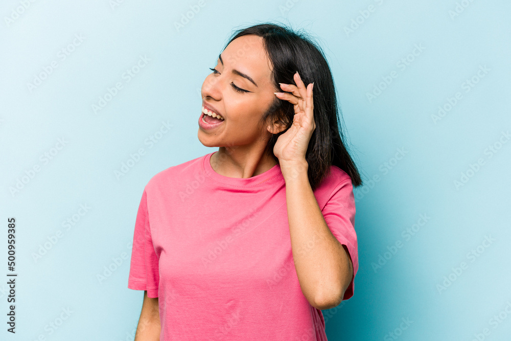 Young hispanic woman isolated on blue background trying to listening a gossip. Young hispanic woman isolated on blue background trying to listening a gossip.