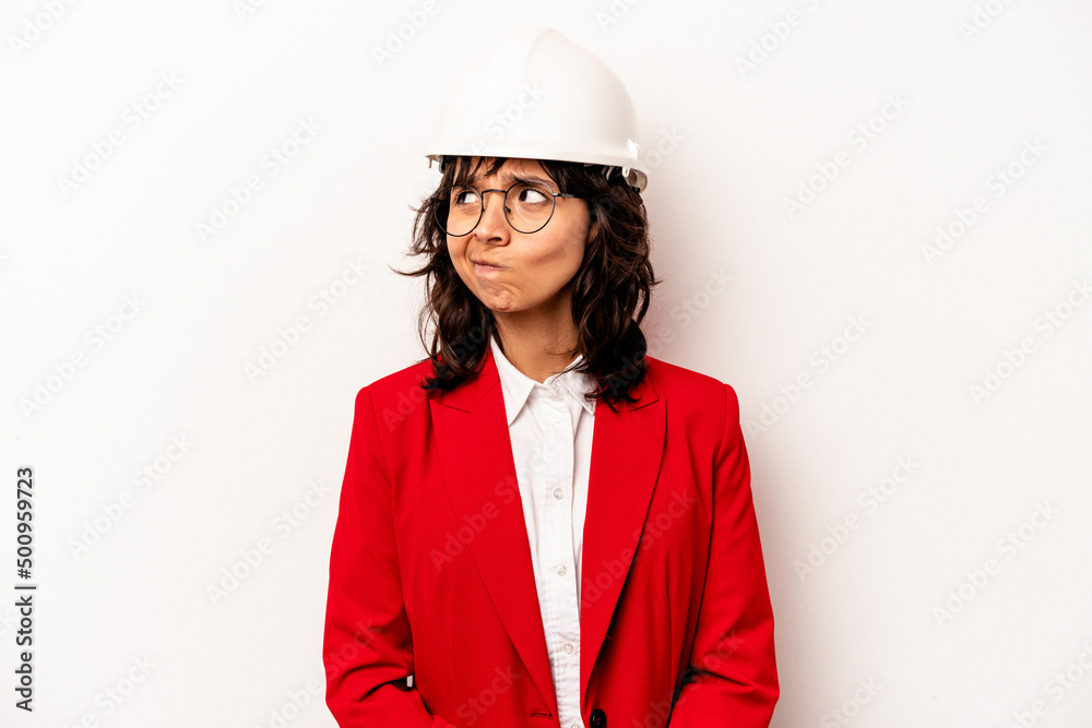 Young architect hispanic woman with helmet isolated on white background confused, feels doubtful and unsure. Young architect hispanic woman with helmet isolated on white background confused, feels doubtful and unsure.
