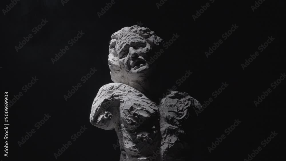 A white statue of a man. A close-up shot on a black background.