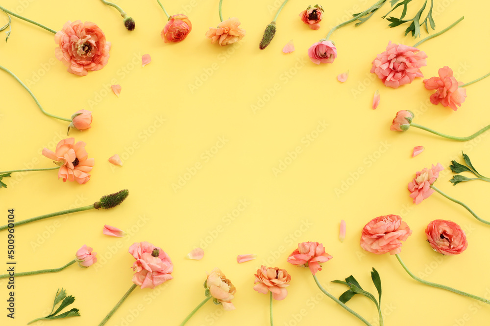 Top view image of pink buttercup flowers composition over yellow pastel background Top view image of pink buttercup flowers composition over yellow pastel background