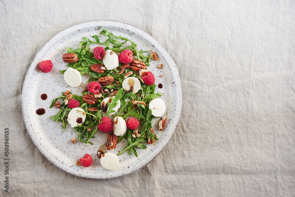 Summer salad with arugula, raspberries, mozzarella cheese and pecan nuts. Morning, breakfast, healthy food. Selective focus Summer salad with arugula, raspberries, mozzarella cheese and pecan nuts. Morning, breakfast, healthy food. Selective focus