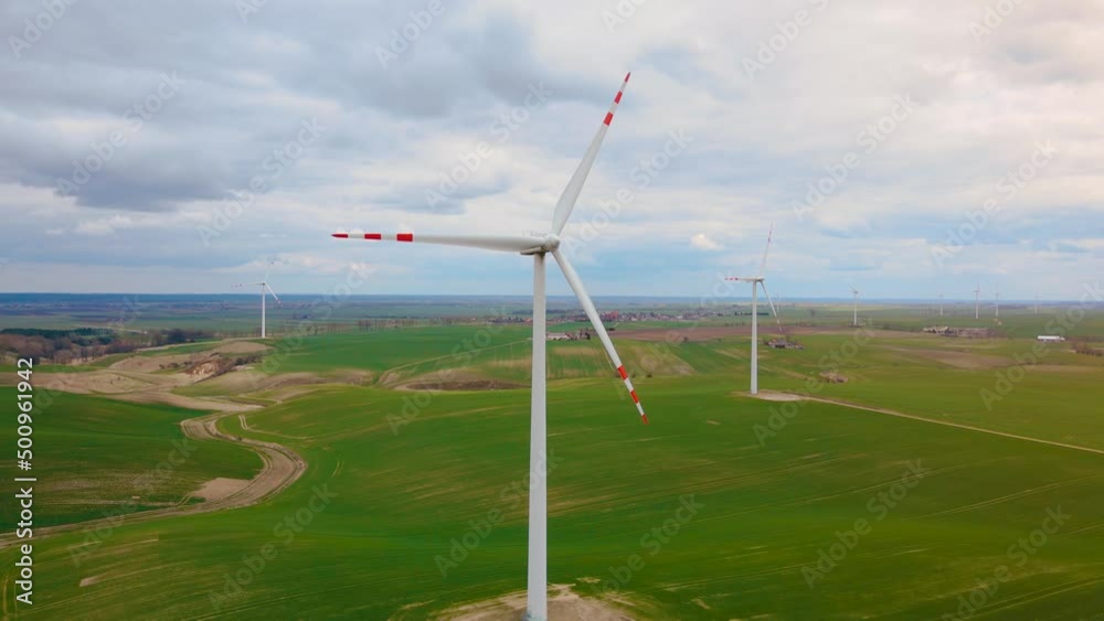 Aerial view large wind turbines standing in farmland and generating clean renewable energy. Electricity saving and concept of alternative power source Aerial view large wind turbines standing in farmland and generating clean renewable energy. Electricity saving and concept of alternative power source