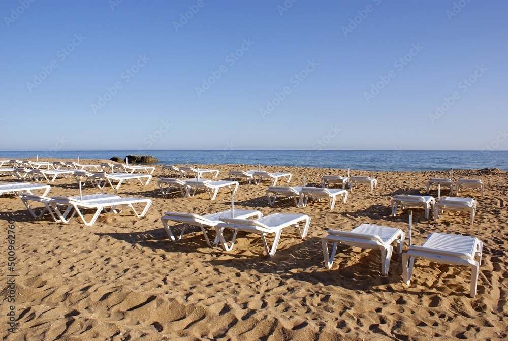 Typical white plastic sunbeds on the beach 