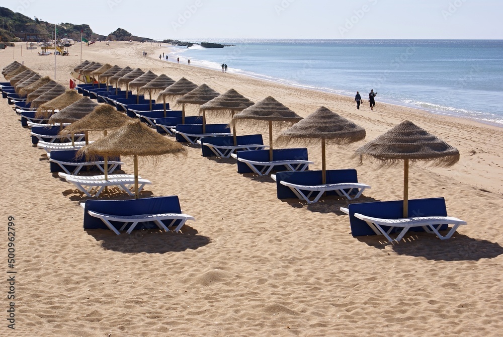 Algarve beach with tropical sun umbrellas and blue sunbeds - Portugal 