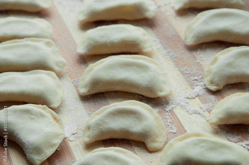 Raw dumplings or varenik. traditional Ukrainian food, close up. dumplings with potatoes on a wooden background. Raw dumplings or varenik. traditional Ukrainian food, close up. dumplings with potatoes on a wooden background.