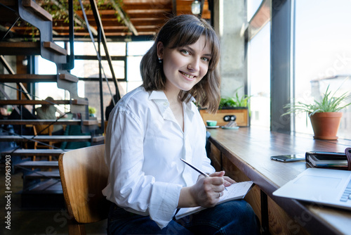 woman manager smiling happily in coworking space. Girl freelancer works in a cafe.