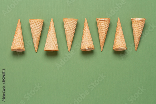 Waffle cones in a row on a green background. Top view  flat lay  copy space.