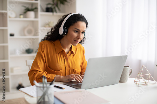 Female Freelancer Using Laptop Wearing Headphones Working Online In Office