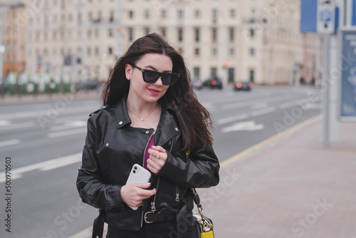 Stylish young girl in a black leather jacket on the street