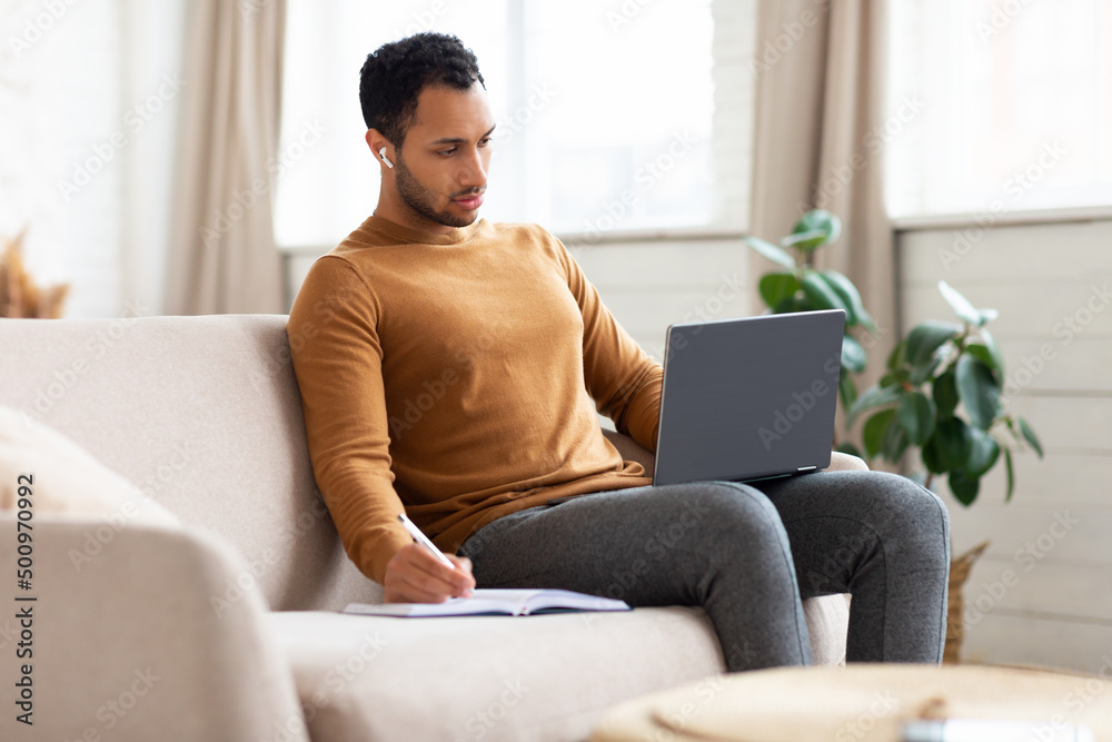 Portrait of focused Arab man using laptop taking notes Portrait of focused Arab man using laptop taking notes