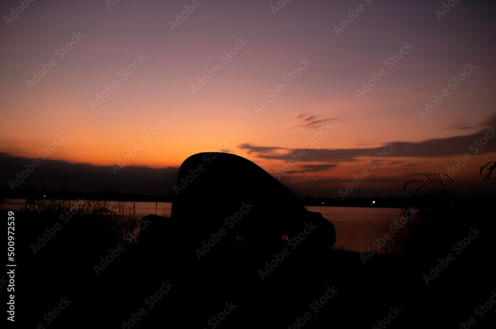 Fototapeta premium Silhouette Young asian muslim man praying on sunset,Ramadan festival concept