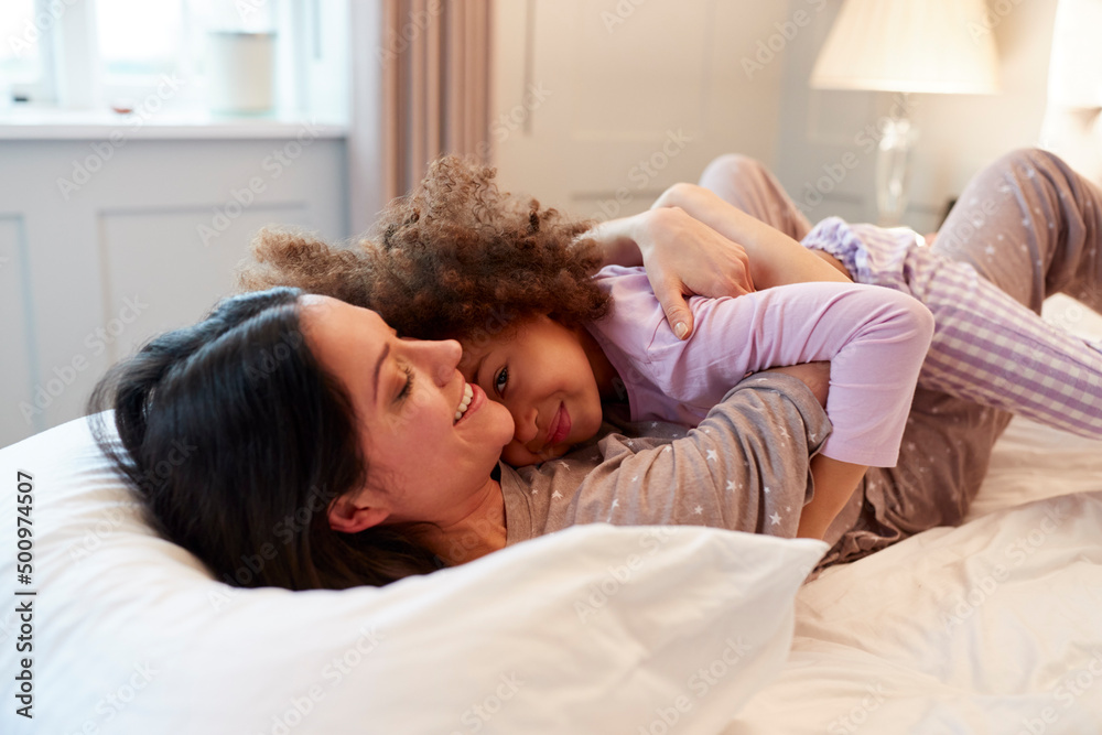 Mother And Daughter Wearing Pyjamas Cuddling On Bed At Home Together Mother And Daughter Wearing Pyjamas Cuddling On Bed At Home Together