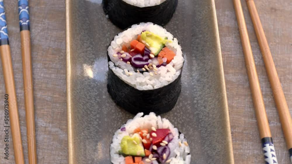 Close-up view of vegan rice rolls with fresh vegetables. Table rotate.
