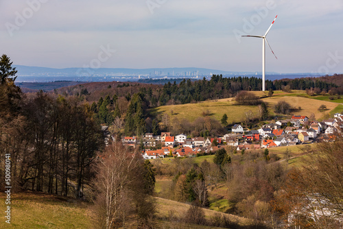 A single wind turbine on a hill above a village