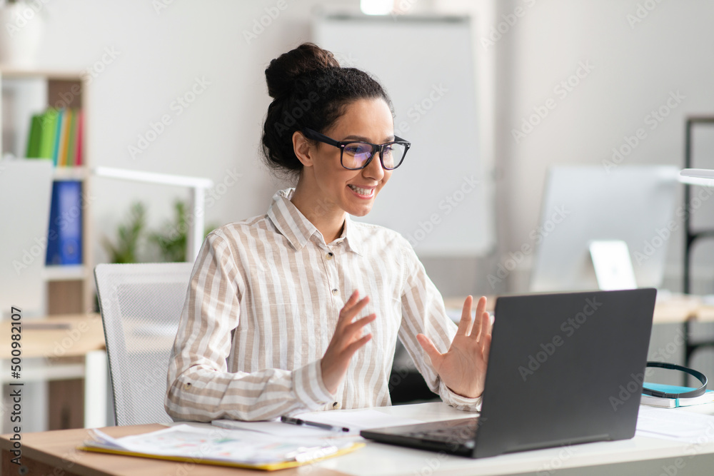 Attractive latin woman having video conference with clients or business partners, sitting at workplace in office Attractive latin woman having video conference with clients or business partners, sitting at workplace in office