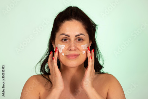 Mature Caucasian woman applying face cream skin care product age 30 to 40