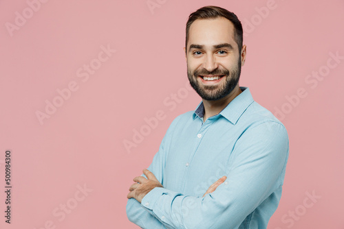 Young smiling cheerful happy caucasian man 20s wear classic blue shirt hold hands crossed folded look camera isolated on plain pastel light pink background studio portrait. People lifestyle concept.