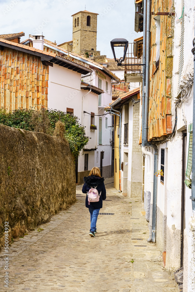 Woman strolling through the narrow streets of the pretty medieval village of Hervas, Caceres.