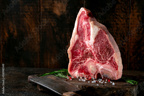 Canvastavla Large raw t-bone steak on a wooden board with seasonings and pepper