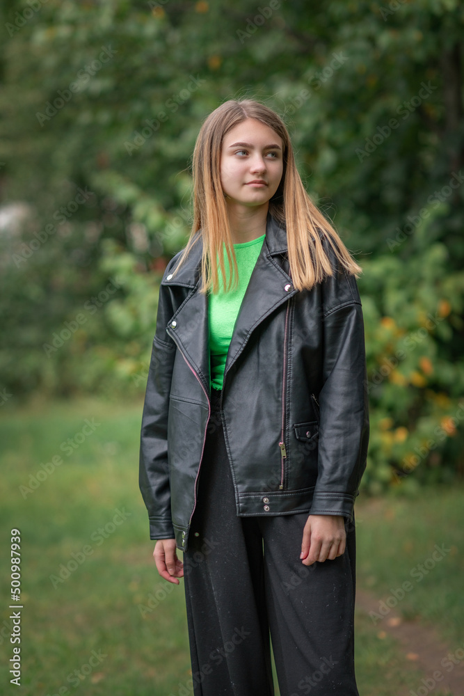 Portrait of a beautiful girl in a dark jacket in the park in early autumn. Portrait of a beautiful girl in a dark jacket in the park in early autumn.