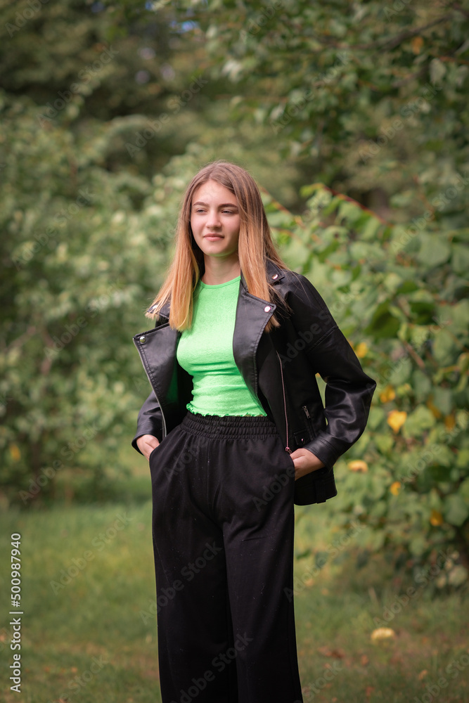 Portrait of a beautiful girl in a dark jacket in the park in early autumn. Portrait of a beautiful girl in a dark jacket in the park in early autumn.