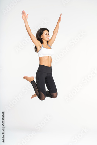 happiness, freedom, power, motion and people concept - smiling young woman jumping in air with raised hands over white background