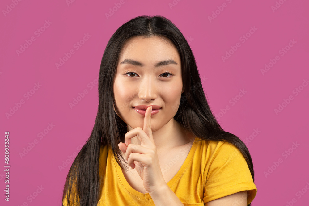 Mysterious asian lady holding finger near lips and looking at camera, pretty woman making shh gesture Mysterious asian lady holding finger near lips and looking at camera, pretty woman making shh gesture