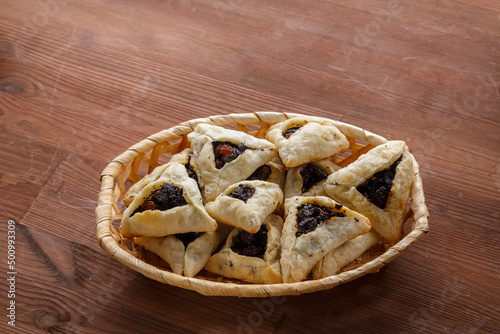 Gomentash with poppy seeds and prunes freshly baked for the Purim holiday on a wooden table in a bread basket.copy space.