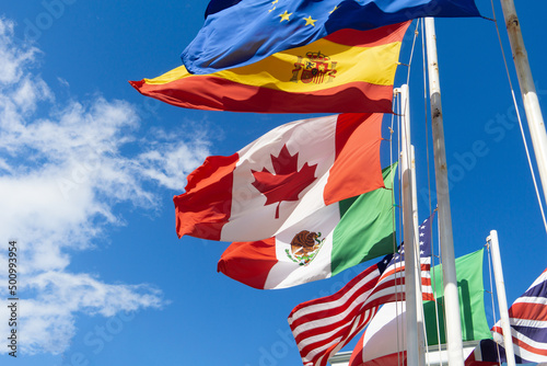 Flags of Canada, Spain, Mexico, the European Union, the USA are developing against the sky. Flags of different countries on flagpoles, the concept of negotiations and international relations.