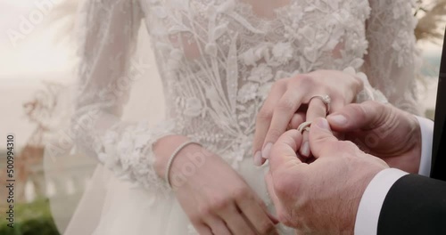 Groom puts marriage ring on bride finger at wedding ceremony