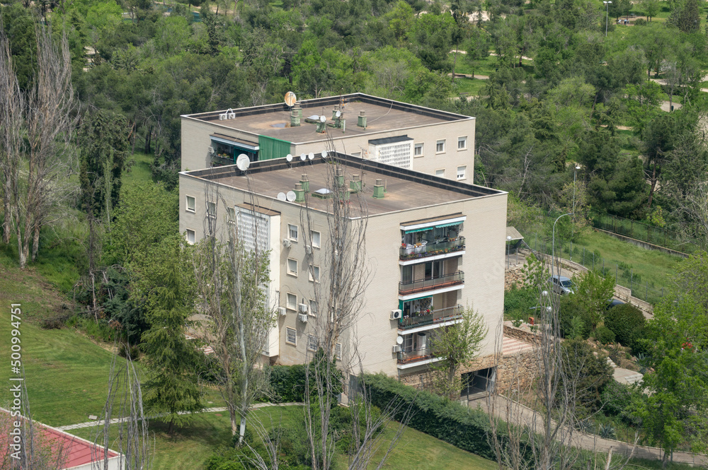 two apartment buildings next to a park two apartment buildings next to a park
