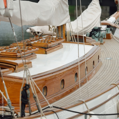 Expensive retro sailing boat (ketch) moored to a pier in a new yacht marina. Wooden teak deck, elegant details. Transportation, nautical vessel, vacations, tourism, cruising, regatta, recreation