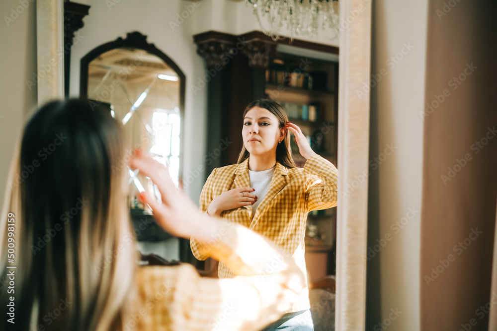 Young attractive caucasian confident woman looking in the mirror at her face. Young attractive caucasian confident woman looking in the mirror at her face.