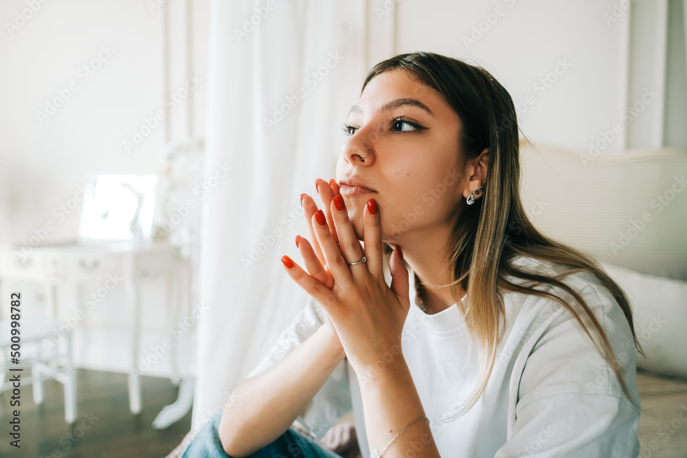 Young bored millennial woman sitting on a bed alone at home. Fatigue or emotionally exhausted concept Young bored millennial woman sitting on a bed alone at home. Fatigue or emotionally exhausted concept