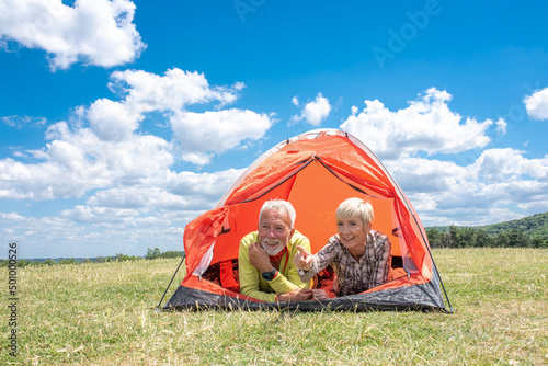 Active senior Caucasian couple lying in tent while taking a break on hike in high mountains 