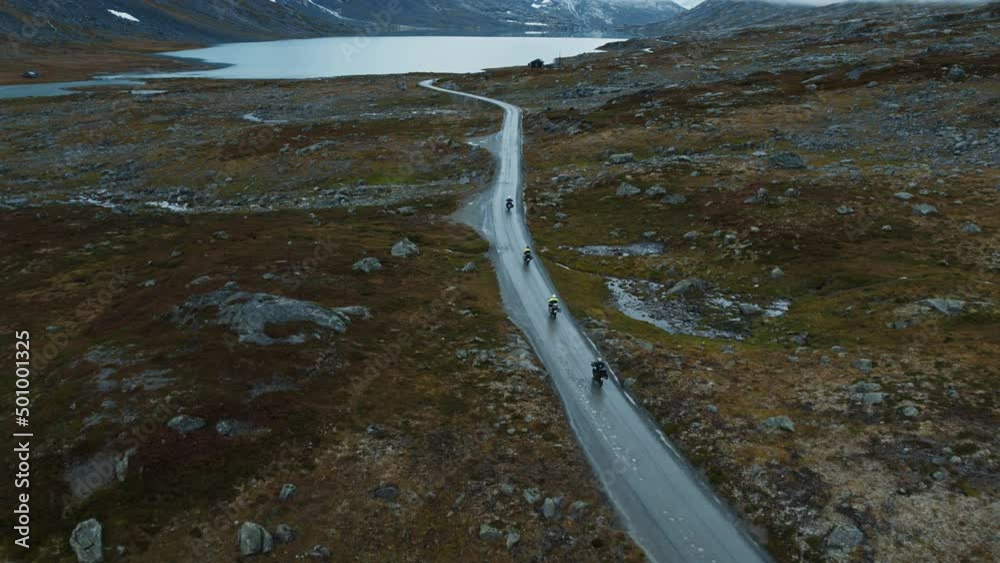 Professional cyclist team on fast and light carbon bicycle descends mountain road to lake in Norway. Fit, athletic team, friends group on recreational ride trip, training camp, enjoying time outdoors