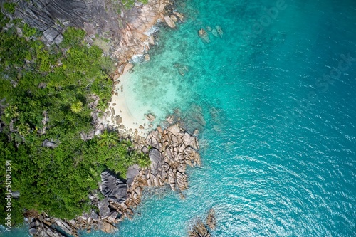 Drone field of view of spectacular blue coastline with waves and forest on Curieuse Island, Seychelles.