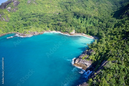 Drone field of view of secret cove with turquoise blue water meeting the forest on secluded island of Mahe, Seychelles. © Tristan Barrington