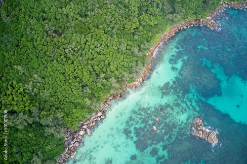 Drone field of view of turquoise blue waters meeting green forest Praslin, Seychelles.