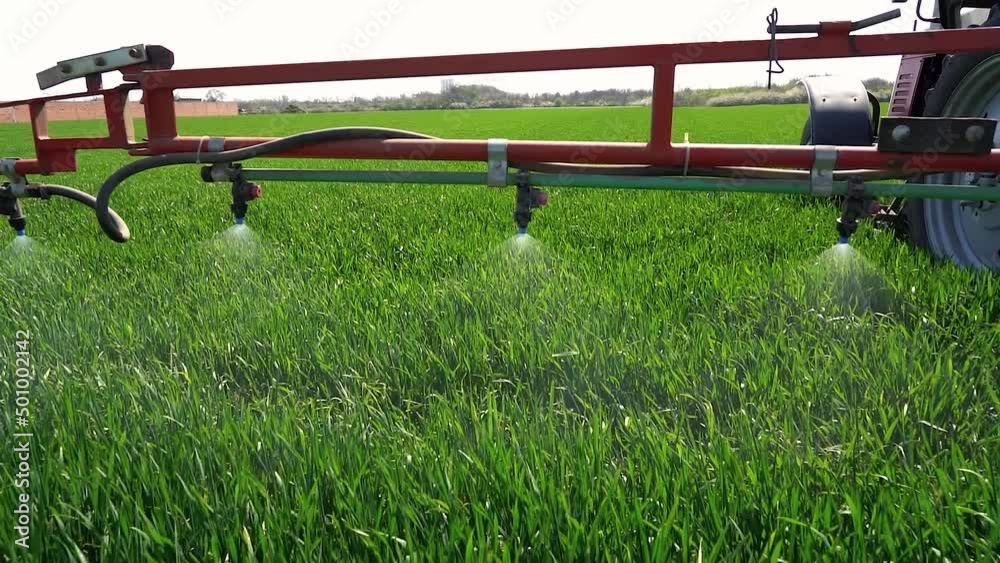 Tractor Spraying A Green Wheat Field - Slow Motion Video. Sprayer Nozzles Spraying Pesticide In A Field Of Wheat. Tractor Mounted Sprayer in Green Wheat Field. Tractor Spraying A Green Wheat Field - Slow Motion Video. Sprayer Nozzles Spraying Pesticide In A Field Of Wheat. Tractor Mounted Sprayer in Green Wheat Field.