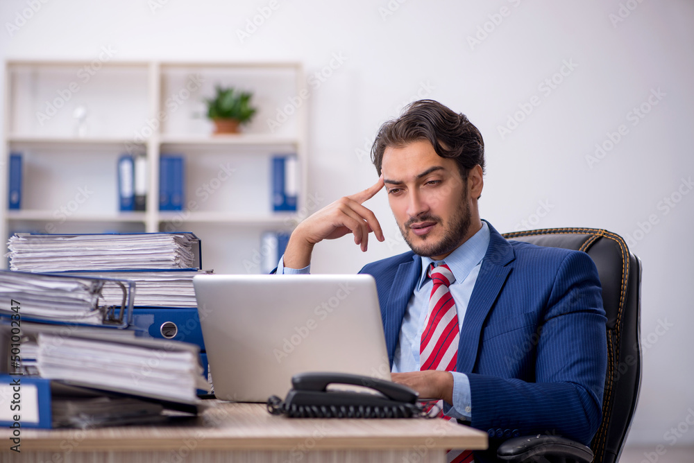 Young male employee and too much work in the office Young male employee and too much work in the office