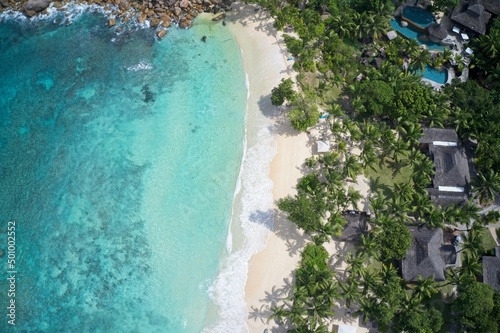 Drone field of view of coastline and houses with spectacular blue bay on Praslin, Seychelles.