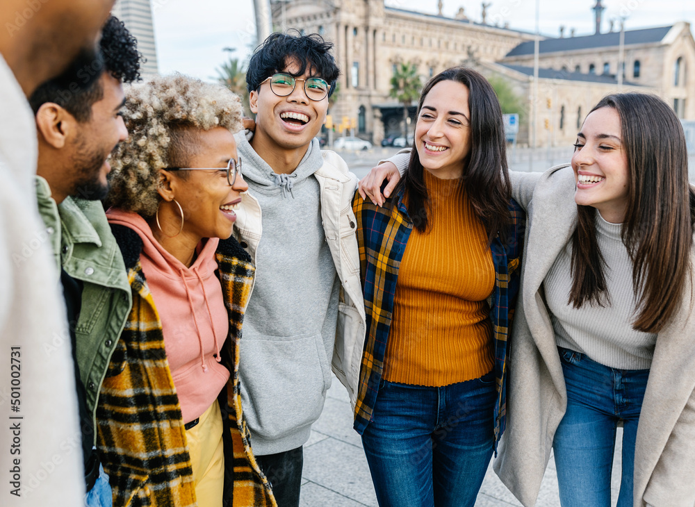 Obraz premium Happy young people laughing together outdoors - Diverse smiling teenager students hugging each other having fun while hanging out in city street