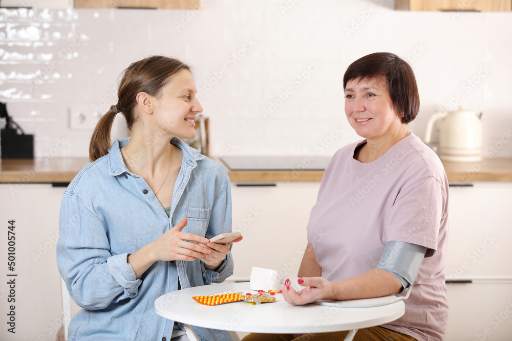 Happy young female providing medical care, helping to support an senior woman on a medical visit at home, a women's care doctor giving a feeling, encouraging a patient to stay at home hospital