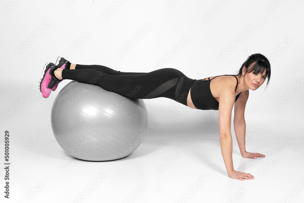 Beautiful fit woman in middle 40 doing exercises with Pilates ball studio shot