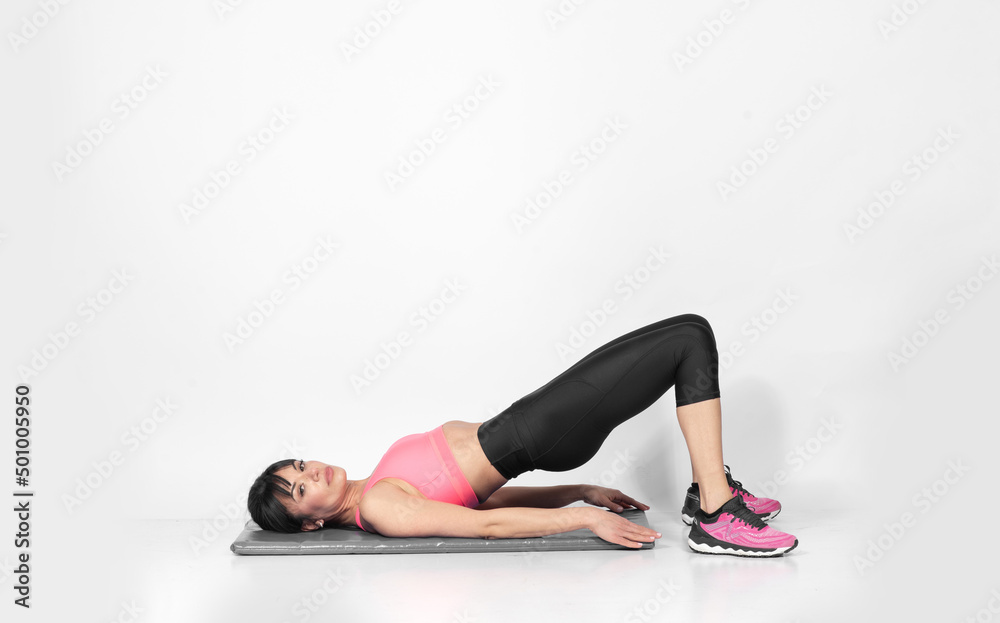Mature fit Caucasian woman doing Pilates stretching exercises  on the floor body sculpturing 
