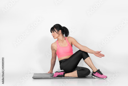 Mature fit Caucasian woman doing Pilates stretching exercises  on the floor body sculpturing 