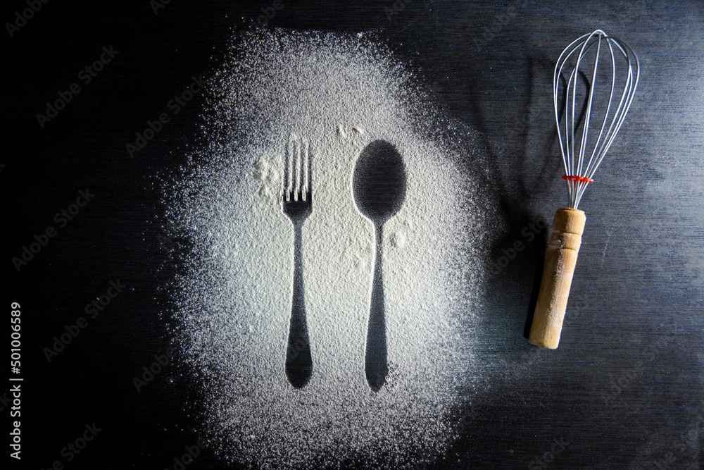 Top view of spoon and fork silhouette made with flour on dark ...